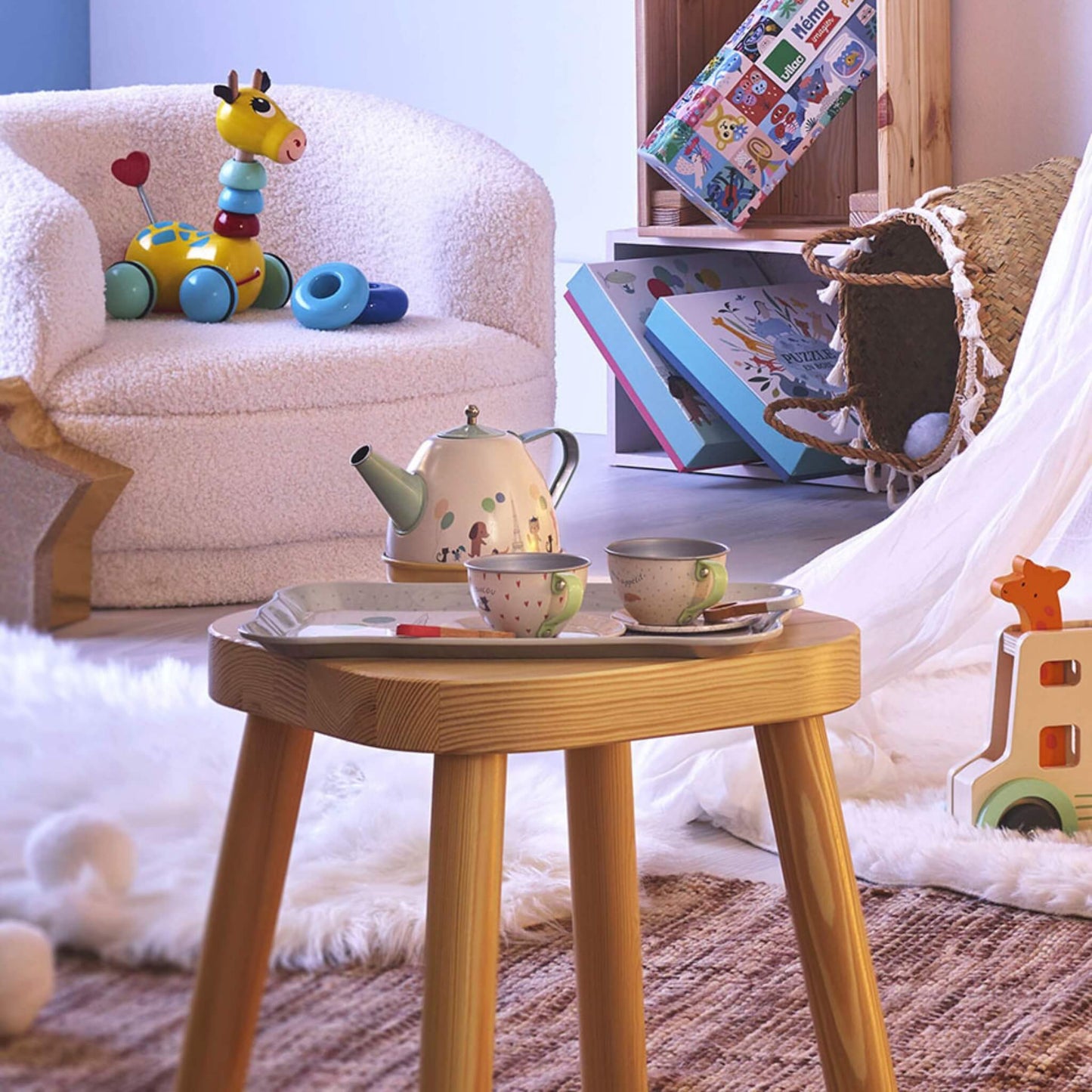 Children's tea set displayed on a wooden table in a playroom with teapot, tray and cups ready for pretend play.