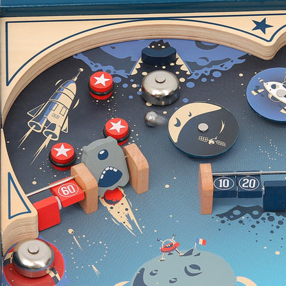 Upper section of pinball game showing bumpers, bell and space-themed artwork with moon and rockets.