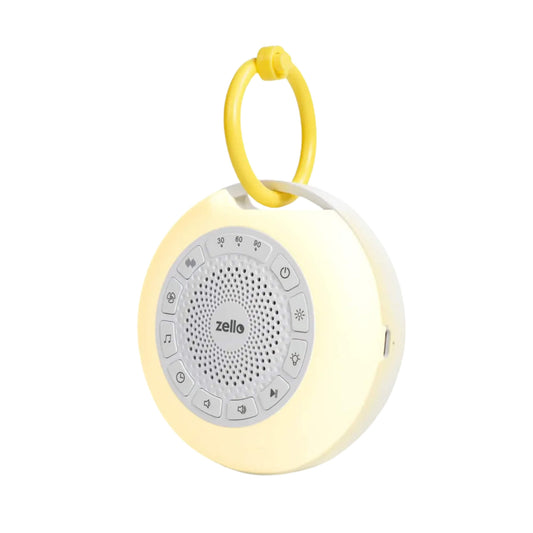 A Zello Portable Pro Max White Noise Machine shown with its soft yellow night light glowing and a yellow clip ring attached, designed for soothing baby sleep on the go.