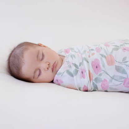 Baby peacefully sleeping swaddled in an Aden + Anais muslin swaddle featuring the Ma Fleur floral print, showcasing soft and breathable fabric.