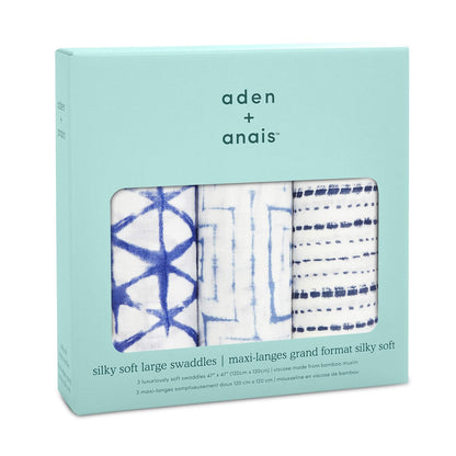 A turquoise retail box with three visible folded swaddles showing indigo geometric prints. The box is branded with the aden + anais logo and product description in English and French.