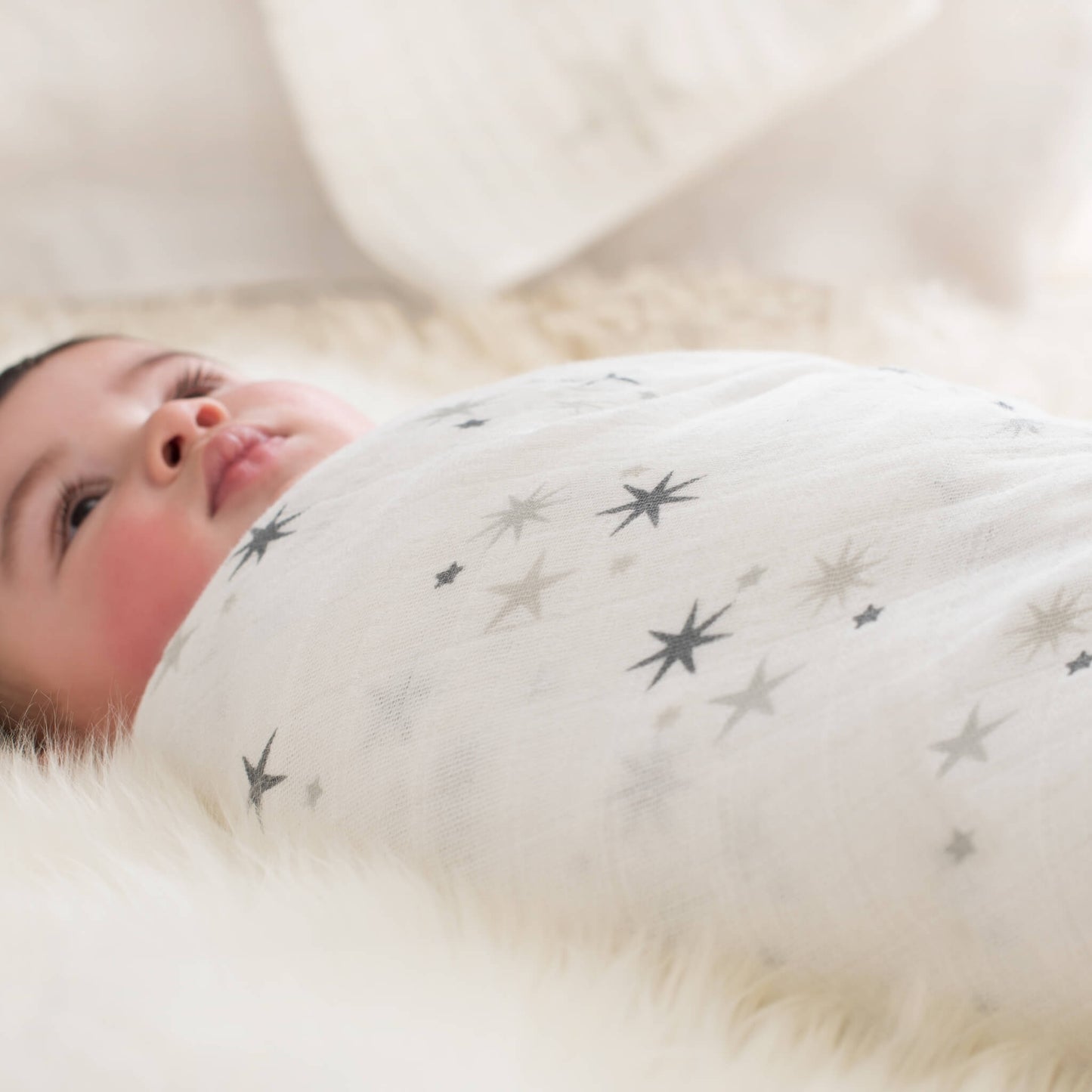 Close-up of baby wrapped in Twinkle star swaddle from aden + anais. Soft muslin fabric with calming star design for newborns.