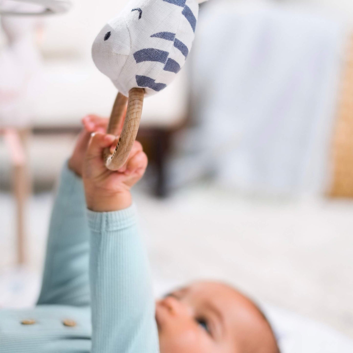Close-up of baby grasping the zebra teething ring toy from the Rising Star collection.

