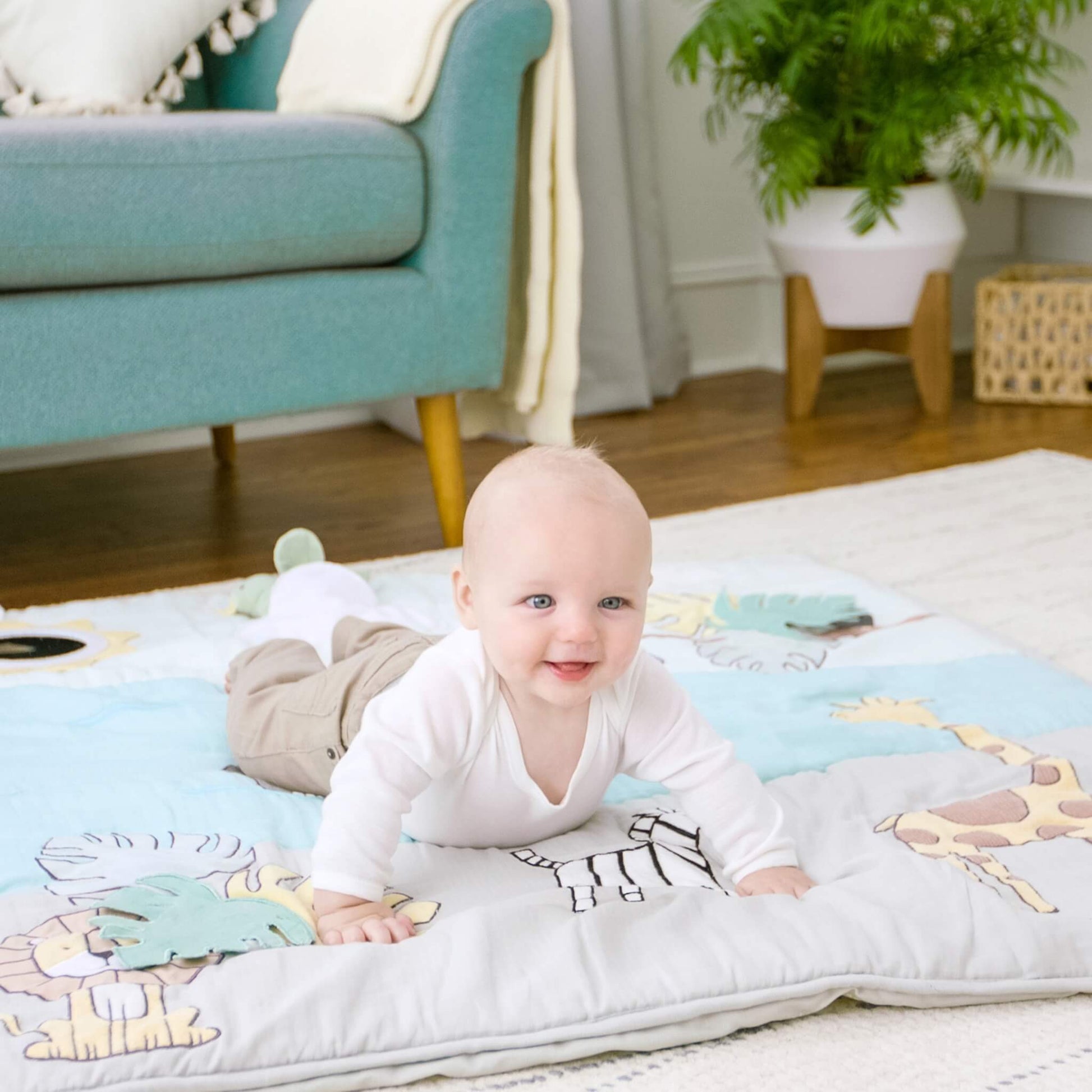 Baby doing tummy time on aden + anais baby playmat with Jungle Jam animals. Playmat supports core strength and early movement on a soft cotton surface.
