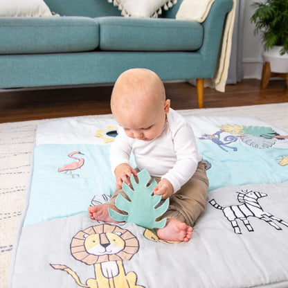 Baby sitting on aden + anais sensory playmat, exploring a crinkle leaf detail. Designed to support fine motor skills and tactile discovery.