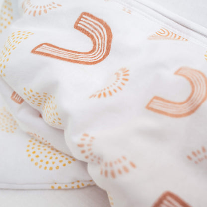 Close-up of soft cotton rainbow print fabric on aden + anais 2.5 TOG sleeping bag. Shows plush texture and warm layers.