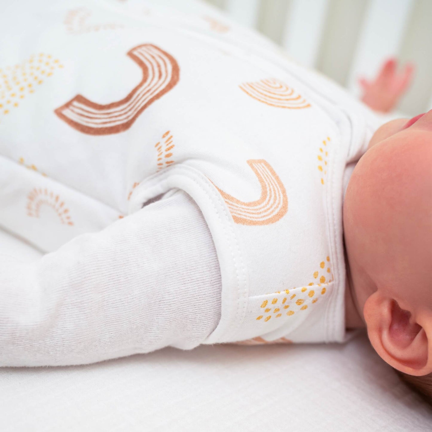 Side view of baby’s arm and shoulder wearing aden + anais Keep Rising sleeping bag. Shows sleeveless design and soft fabric details.