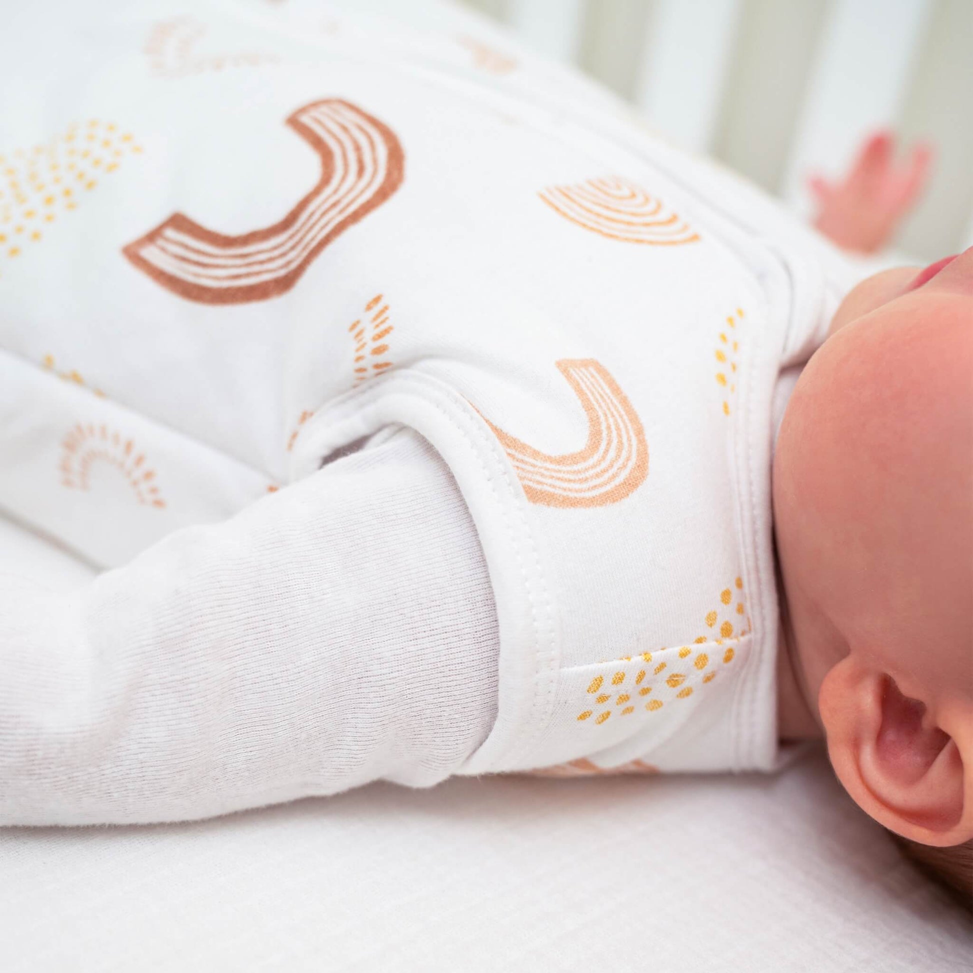 Side view of baby’s arm and shoulder wearing aden + anais Keep Rising sleeping bag. Shows sleeveless design and soft fabric details.