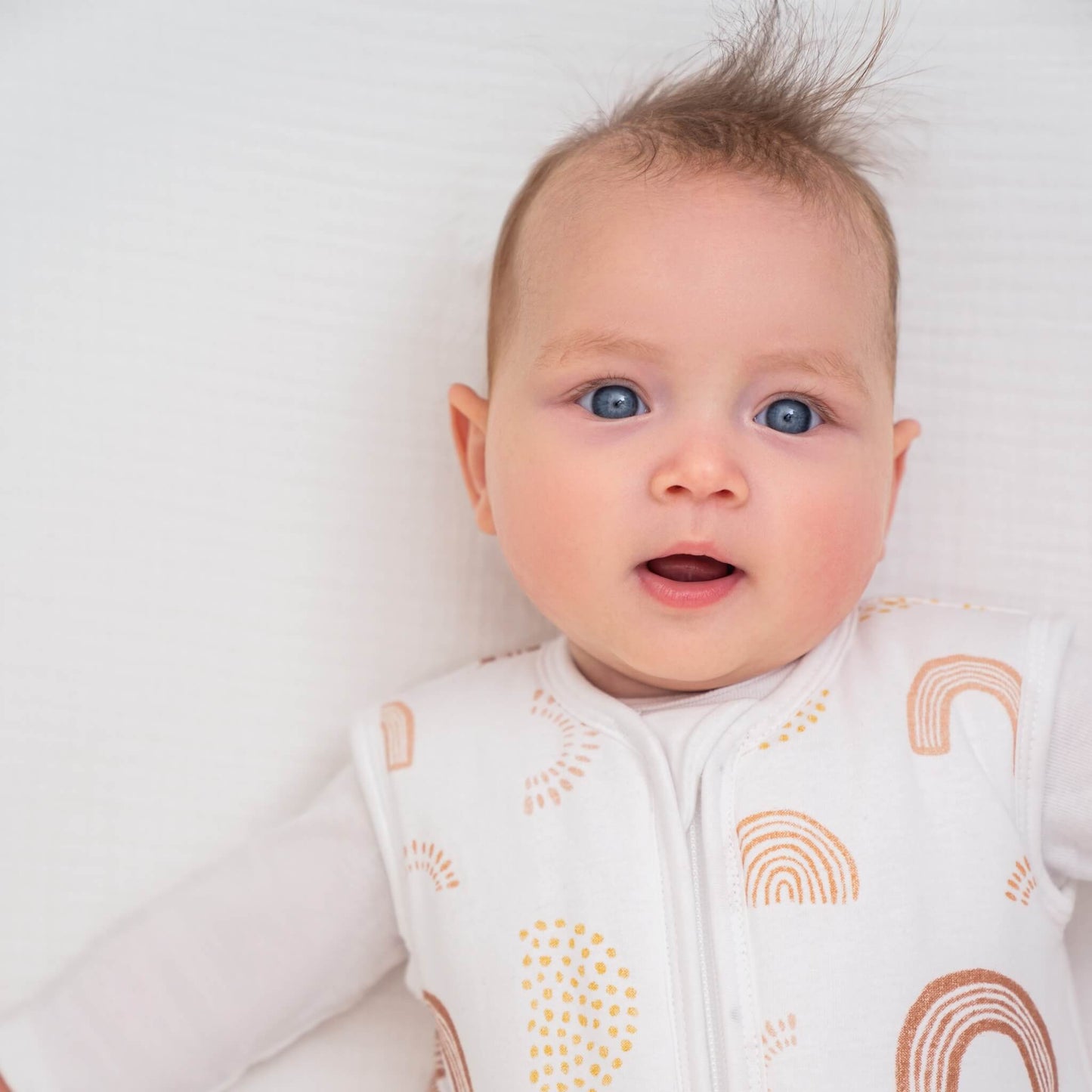 Baby in cot wearing aden + anais 2.5 TOG sleeping bag in Keep Rising print. Gentle neckline and breathable design shown in detail.