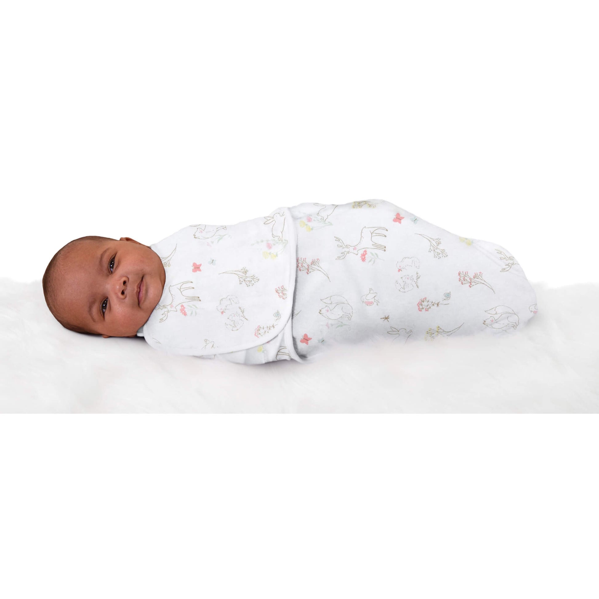Newborn wrapped in aden + anais woodland animal print swaddle, lying on a soft surface and looking up calmly.