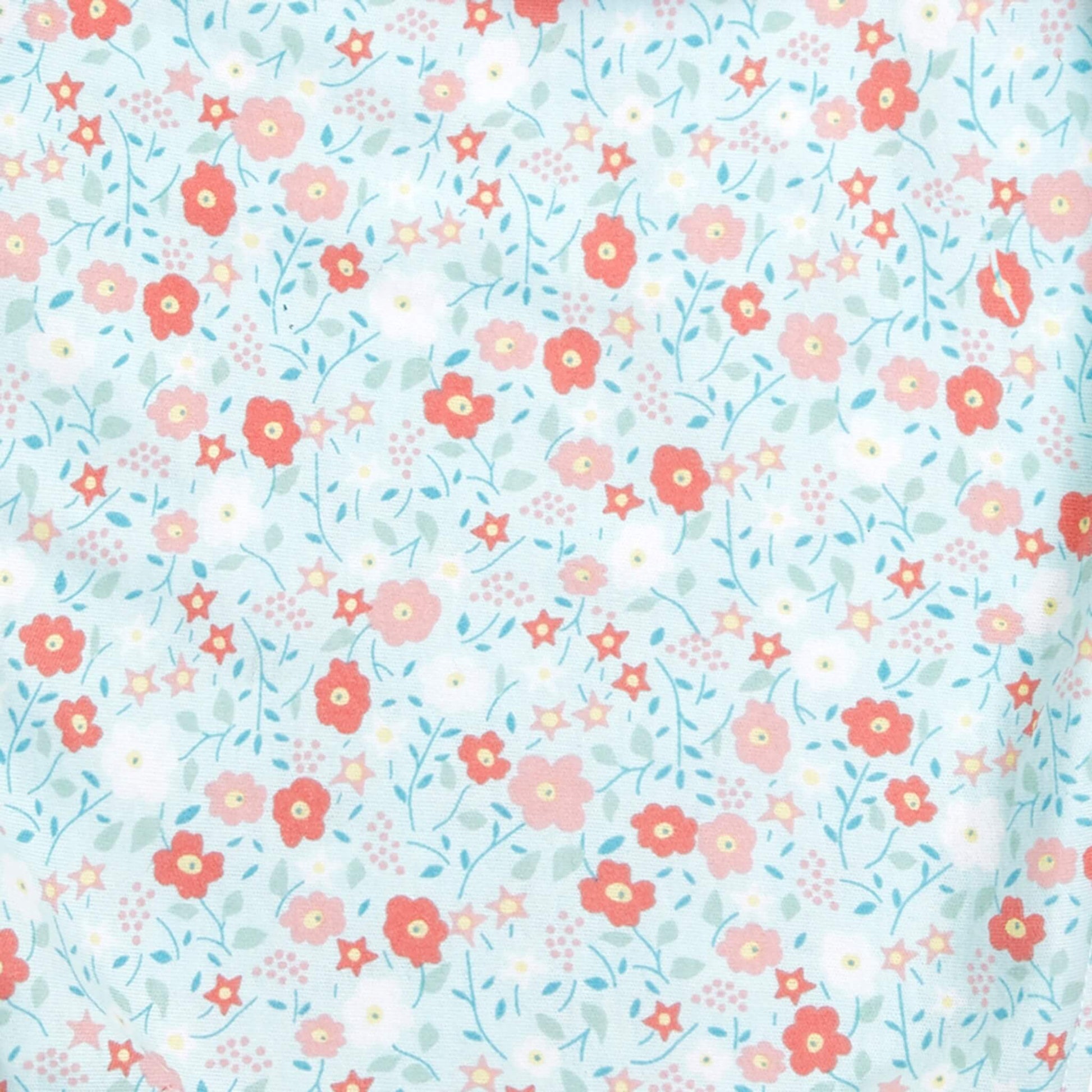 Close-up of aden + anais floral print fabric with red, pink, and white flowers on a light blue background.