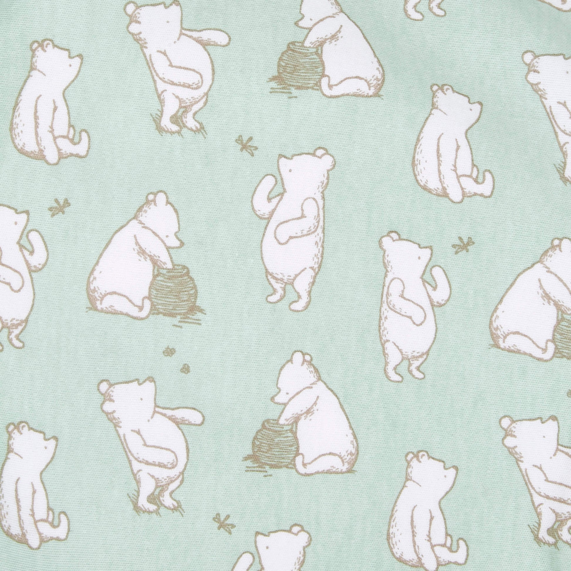 A close-up of green swaddle fabric with repeated illustrations of Winnie the Pooh in beige outline, showing various seated and standing poses with honey pots and bees.