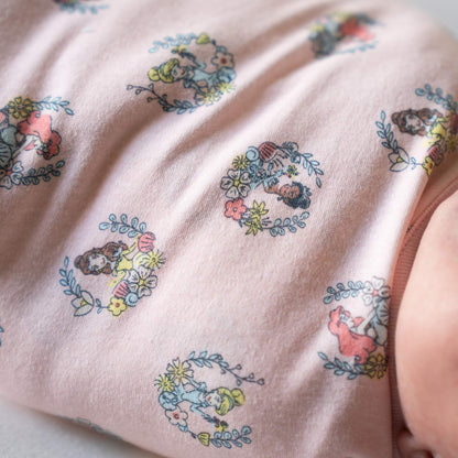 A close-up of the pink swaddle fabric, showing cartoon-style princess faces within floral rings, printed on soft pink material.