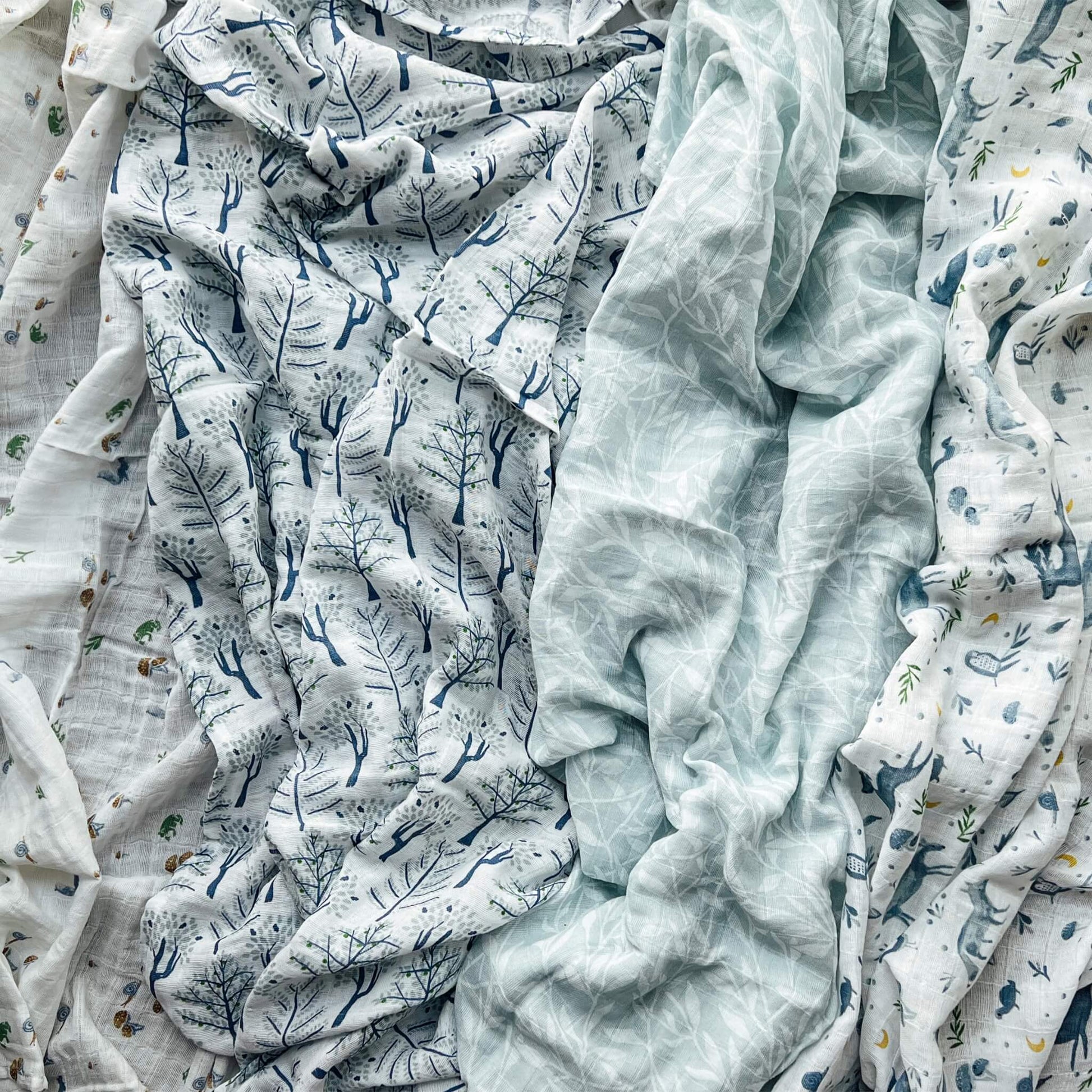 aden + anais Outdoors muslin swaddle set laid out flat showing nature-inspired prints in soft blue and green tones.
