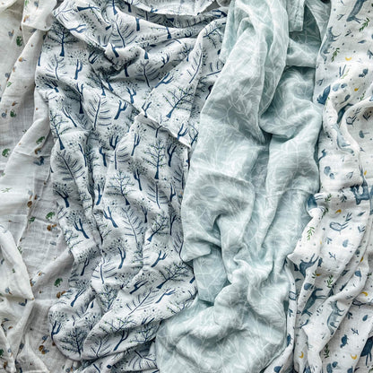 aden + anais Outdoors muslin swaddle set laid out flat showing nature-inspired prints in soft blue and green tones.