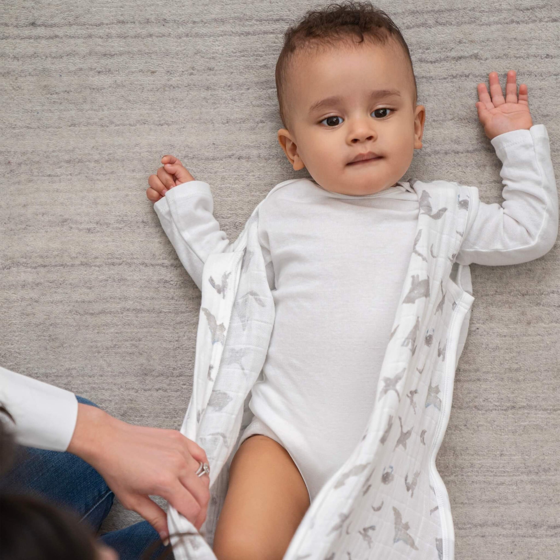 Baby lying in aden + anais Map the Stars sleeping bag. Soft, breathable muslin layer for safe, comfortable sleep.
