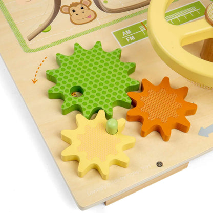 Close-up of three interlocking wooden gears in green, yellow and orange attached to a pale wooden activity board.