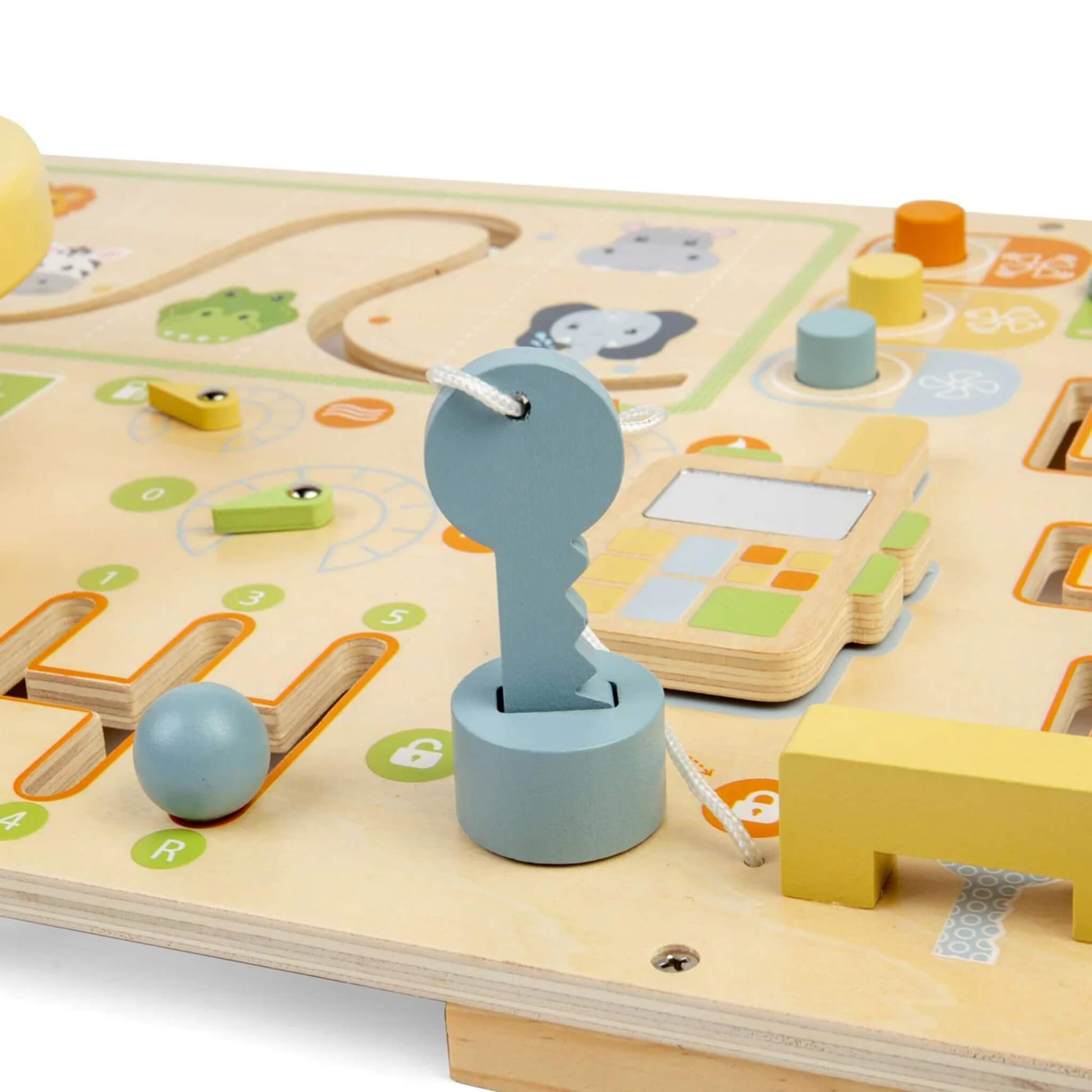 Close-up of a wooden key attached with white cord beside a pretend phone and sliding lock mechanism on a sensory busy board.