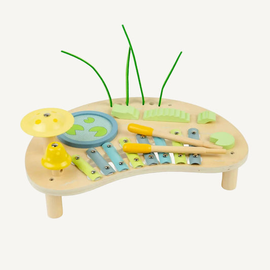 Wooden jungle-themed music bench with pastel xylophone bars, spinning drum sections, textured sensory pieces and two wooden beaters resting across the instrument.
