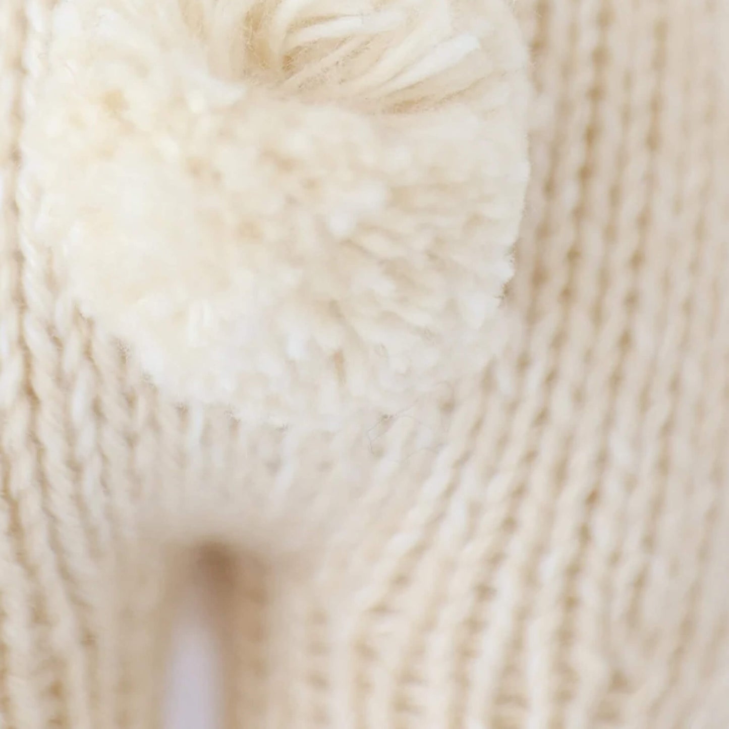 Close-up of knitted bunny tail showing soft yarn texture and detailed stitching.