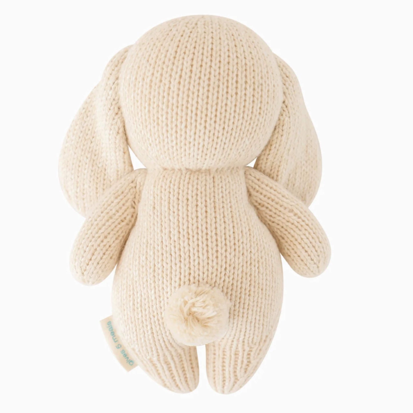 Back view of knitted bunny soft toy showing rounded shape, floppy ears and pom-pom tail.