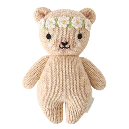 Cuddle + Kind Baby Animal Honey Bear Ivory Floral soft knitted teddy with stitched face and daisy flower crown on a neutral background.