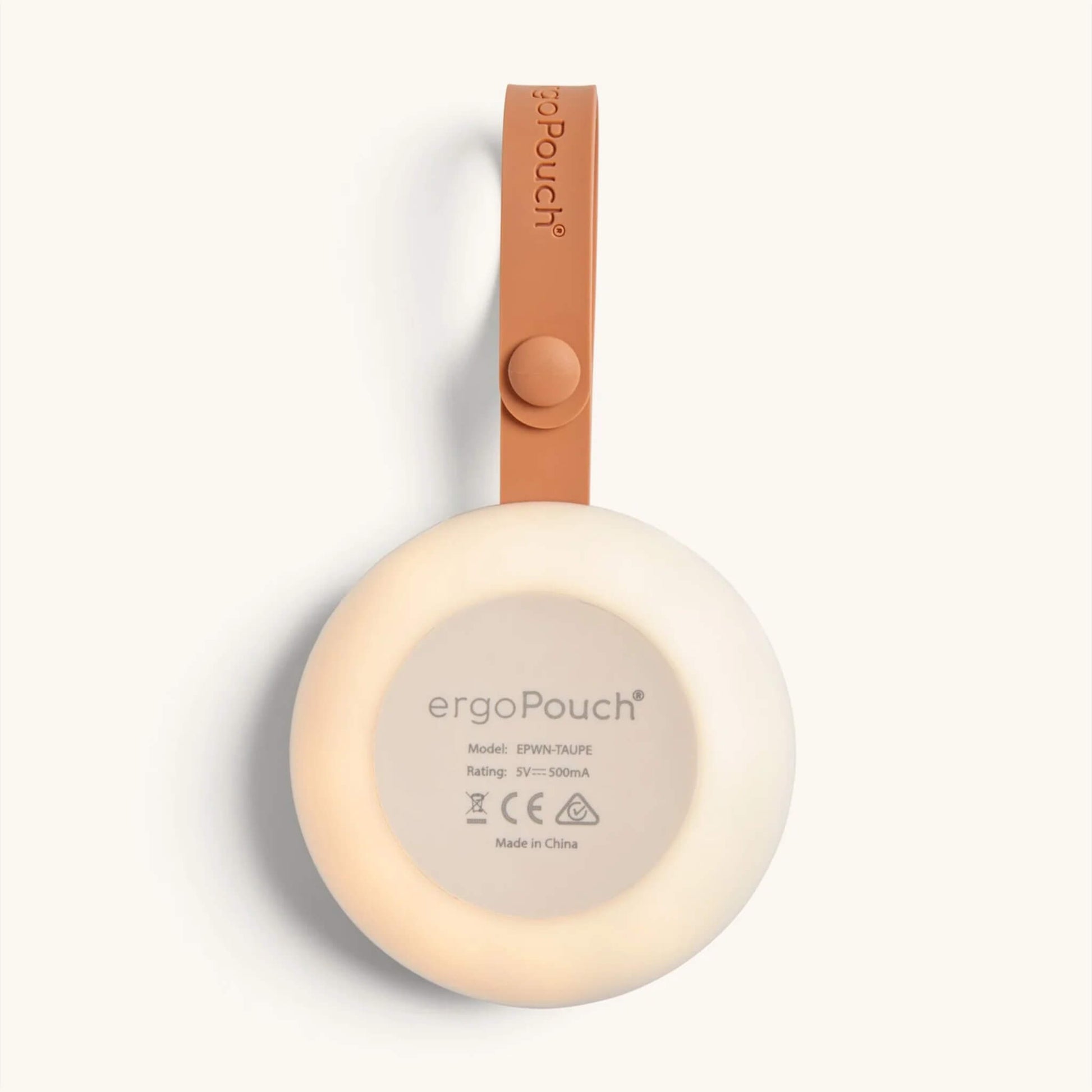 Underside view of a portable white noise machine showing the glowing nightlight ring, product details printed on the base, and an orange strap embossed with the ergoPouch logo.