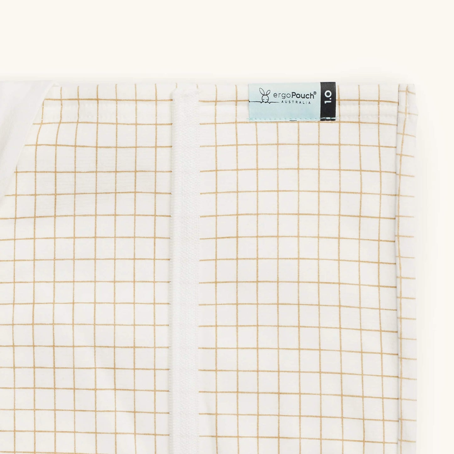 Close-up of a caramel grid patterned blanket with a fabric label on the seam.