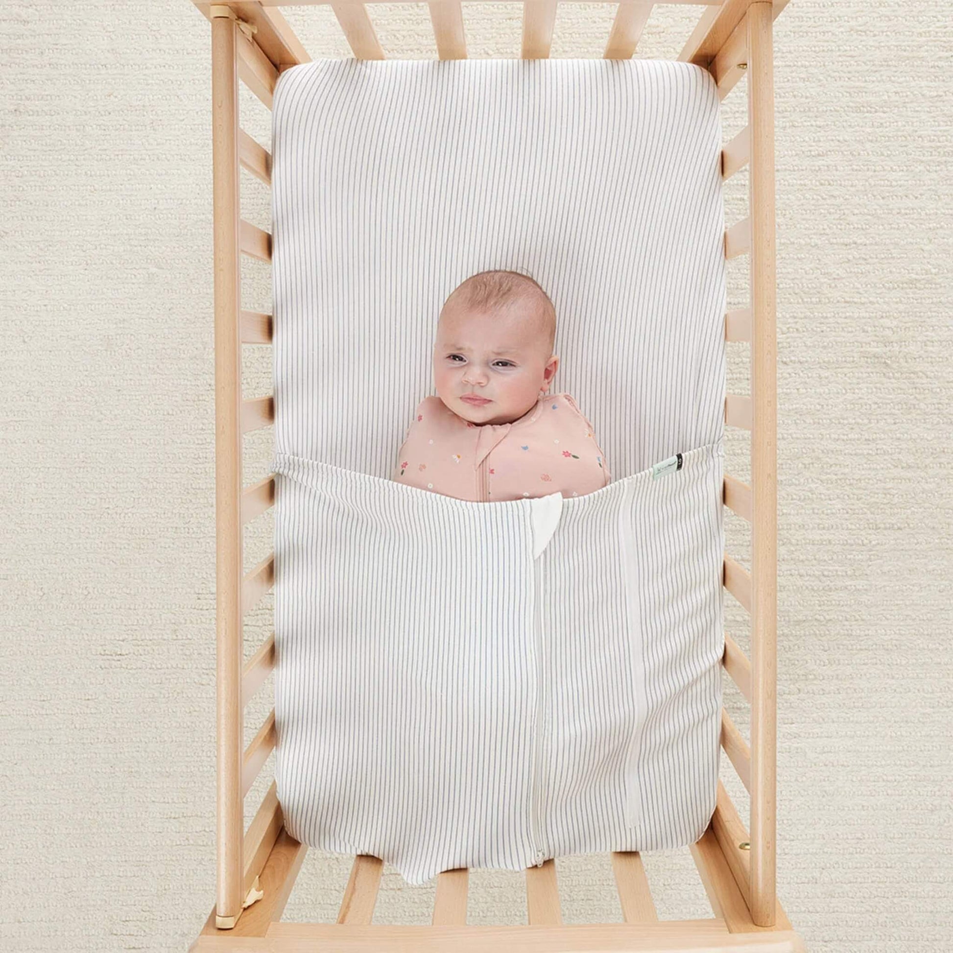 Top view of a baby tucked in with the HugMe Blanket in midnight stripe, highlighting the snug yet safe design.