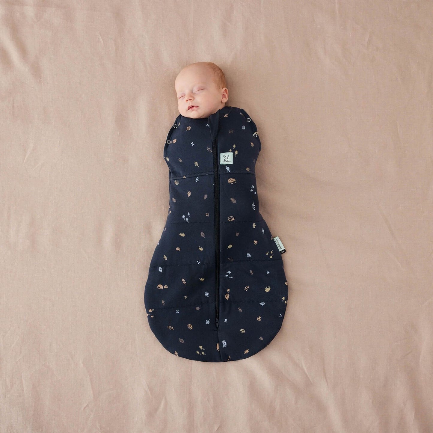 Baby wrapped snugly in a winter weight Cocoon Swaddle Bag with hedgehog print, zip-up front, and bell-shaped bottom.