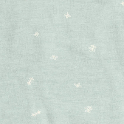 Close-up of sage green cotton fabric patterned with tiny white leaf motifs from the Cocoon Swaddle Bag.