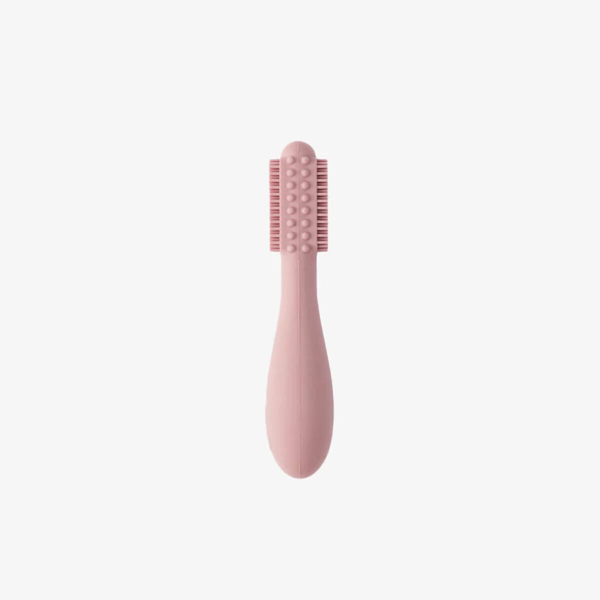 Blush pink silicone baby toothbrush showing soft bristles on both sides with raised sensory bumps along a rounded head and a thick easy-grip handle for small hands.