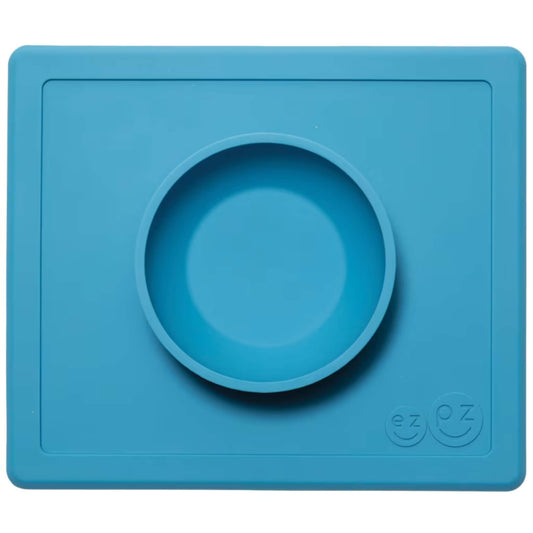 ezpz Happy Bowl in blue. A round silicone bowl is built into a rectangular placemat with the ezpz smiley face logo embossed in the corner.