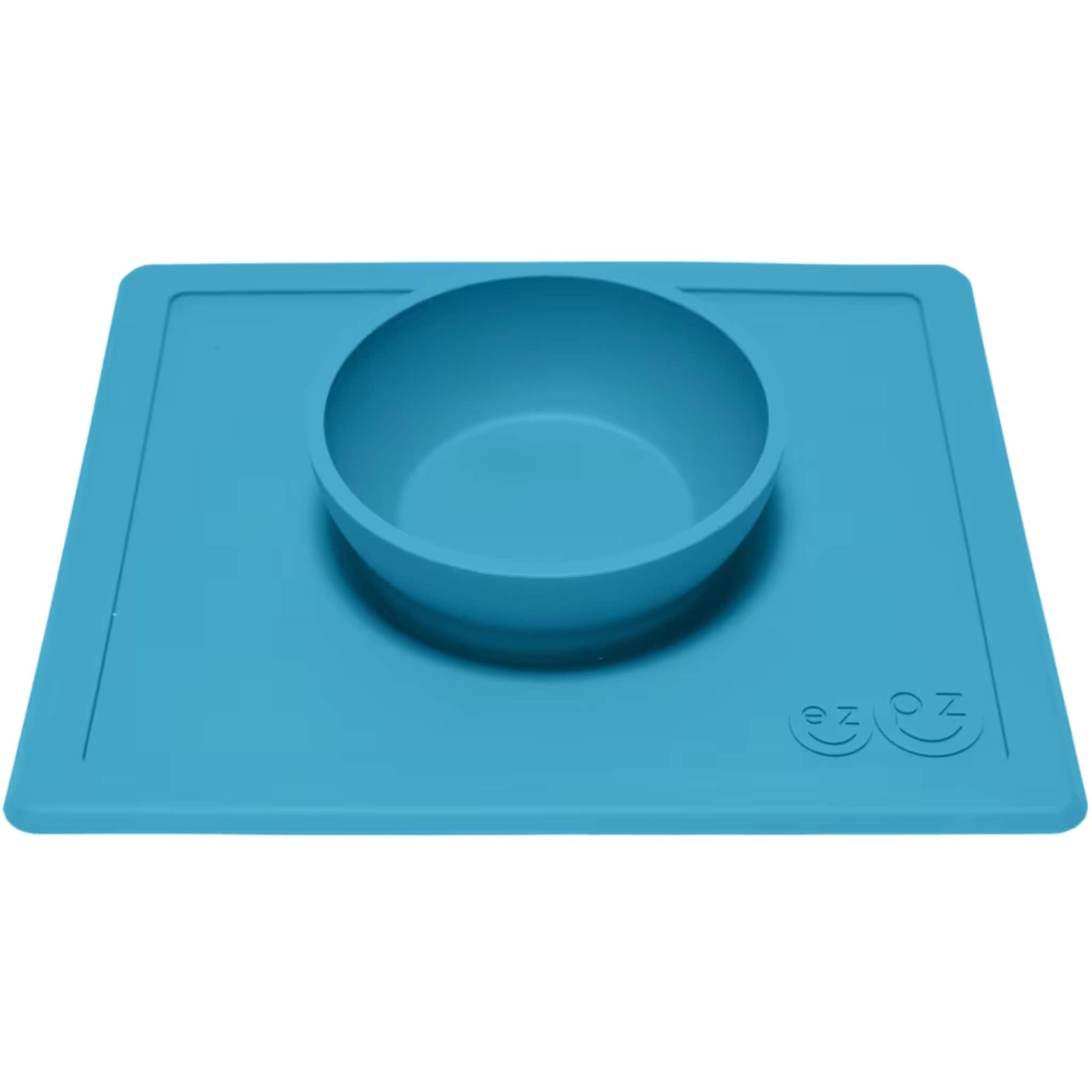 Blue silicone feeding bowl attached to a flat rectangular placemat, shown from an angle to highlight the depth of the bowl.