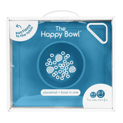 Retail packaging box showing the Happy Bowl in blue. The front displays a product illustration, the name “The Happy Bowl” and the description placemat + bowl in one.