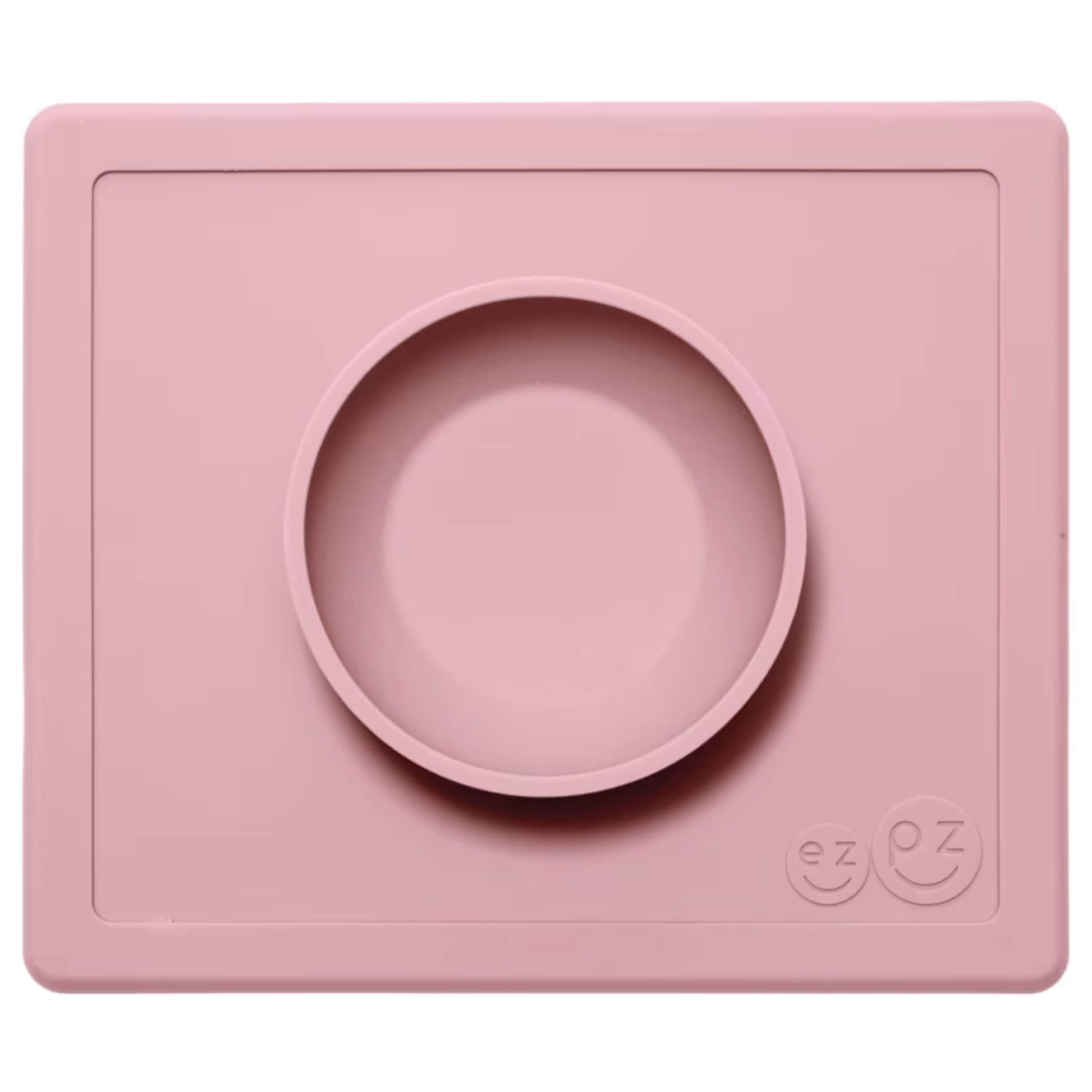 ezpz Happy Bowl in blush. A round silicone bowl is built into a rectangular placemat with the ezpz smiley face logo embossed in the corner.