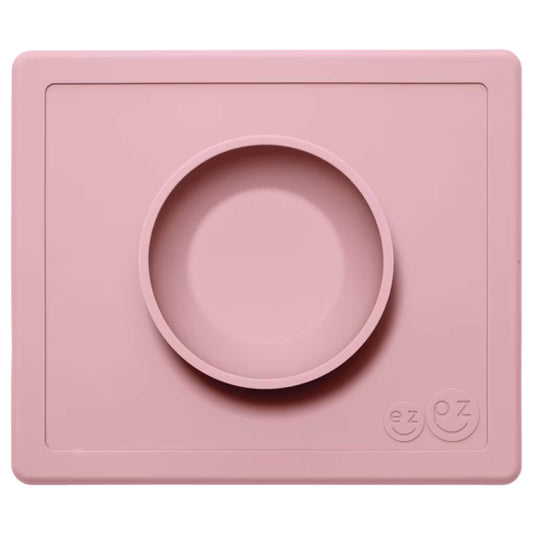 ezpz Happy Bowl in blush. A round silicone bowl is built into a rectangular placemat with the ezpz smiley face logo embossed in the corner.
