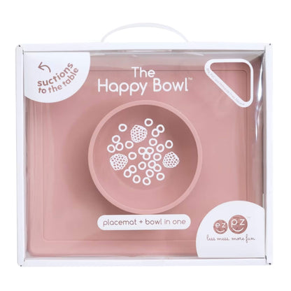 Retail packaging box showing the Happy Bowl in blush. The front displays a product illustration, the name “The Happy Bowl” and the description placemat + bowl in one.