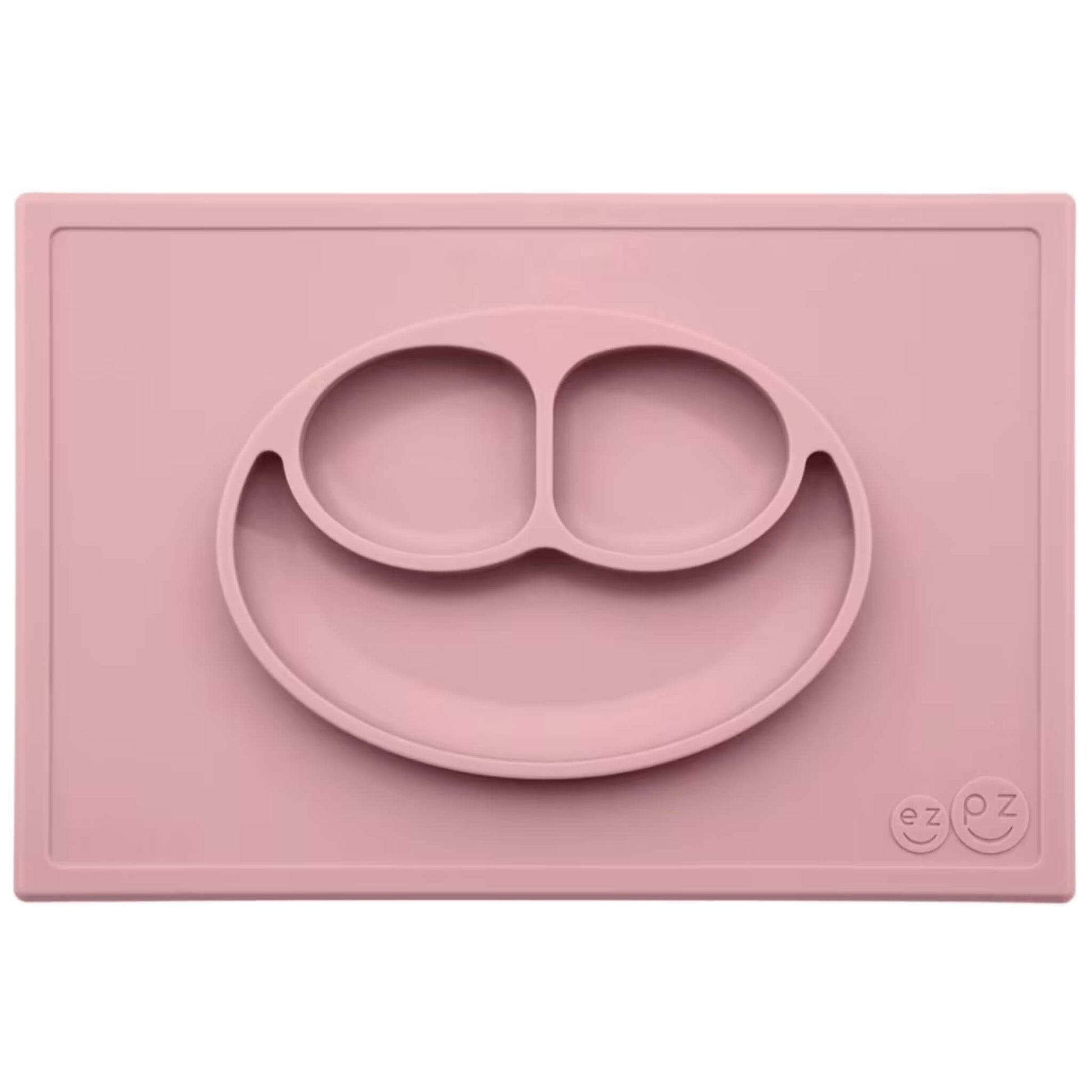Ezpz Happy Mat in blush pink, a silicone placemat and plate in one with three compartments in a smiley face design to make toddler mealtimes easier.