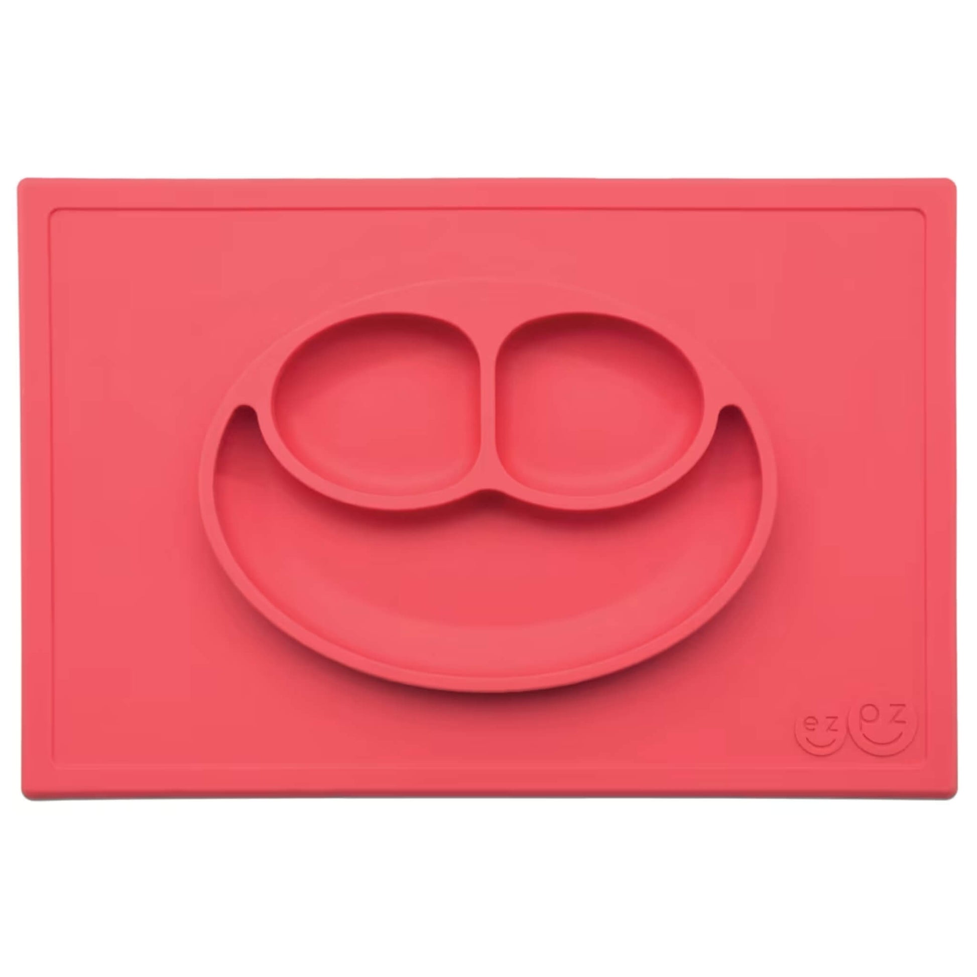 Ezpz Happy Mat in coral red, a silicone placemat and plate in one with three compartments in a smiley face design to make toddler mealtimes easier.