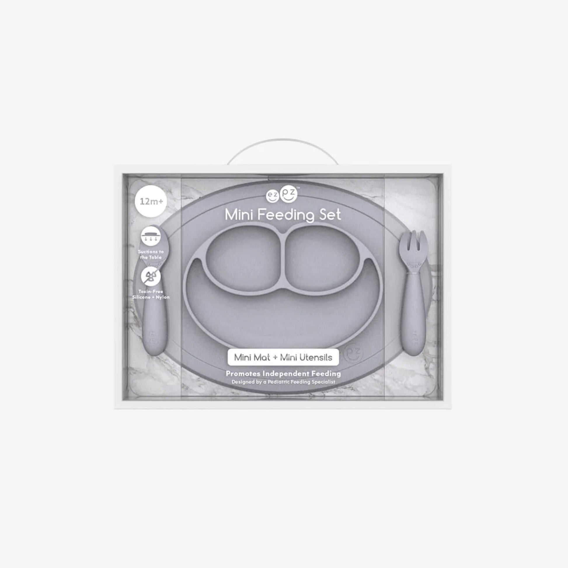 Boxed Ezpz Mini Feeding Set in Pewter displayed in retail packaging with the mat and utensils visible through the clear front.
