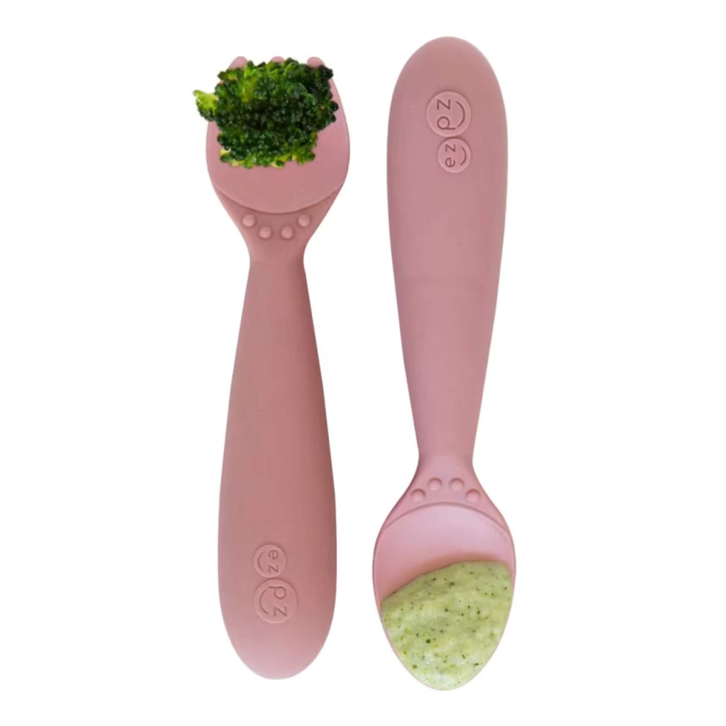 Blush silicone toddler fork holding a piece of broccoli next to a matching spoon filled with vegetable puree.