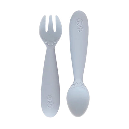 Ezpz Mini Utensils in pewter grey, a silicone toddler fork and spoon set with rounded handles for safe self-feeding.