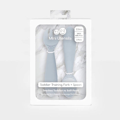 Boxed set of Ezpz Mini Utensils in pewter grey showing a toddler training fork and spoon displayed in retail packaging.