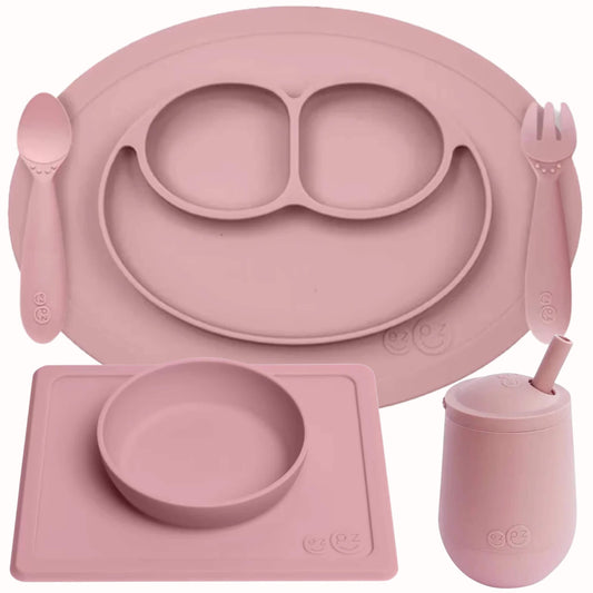 ezpz Self-Feeding Mealtime Bundle in blush featuring a silicone mini mat with spoon and fork, suction bowl with placemat and mini cup with straw.