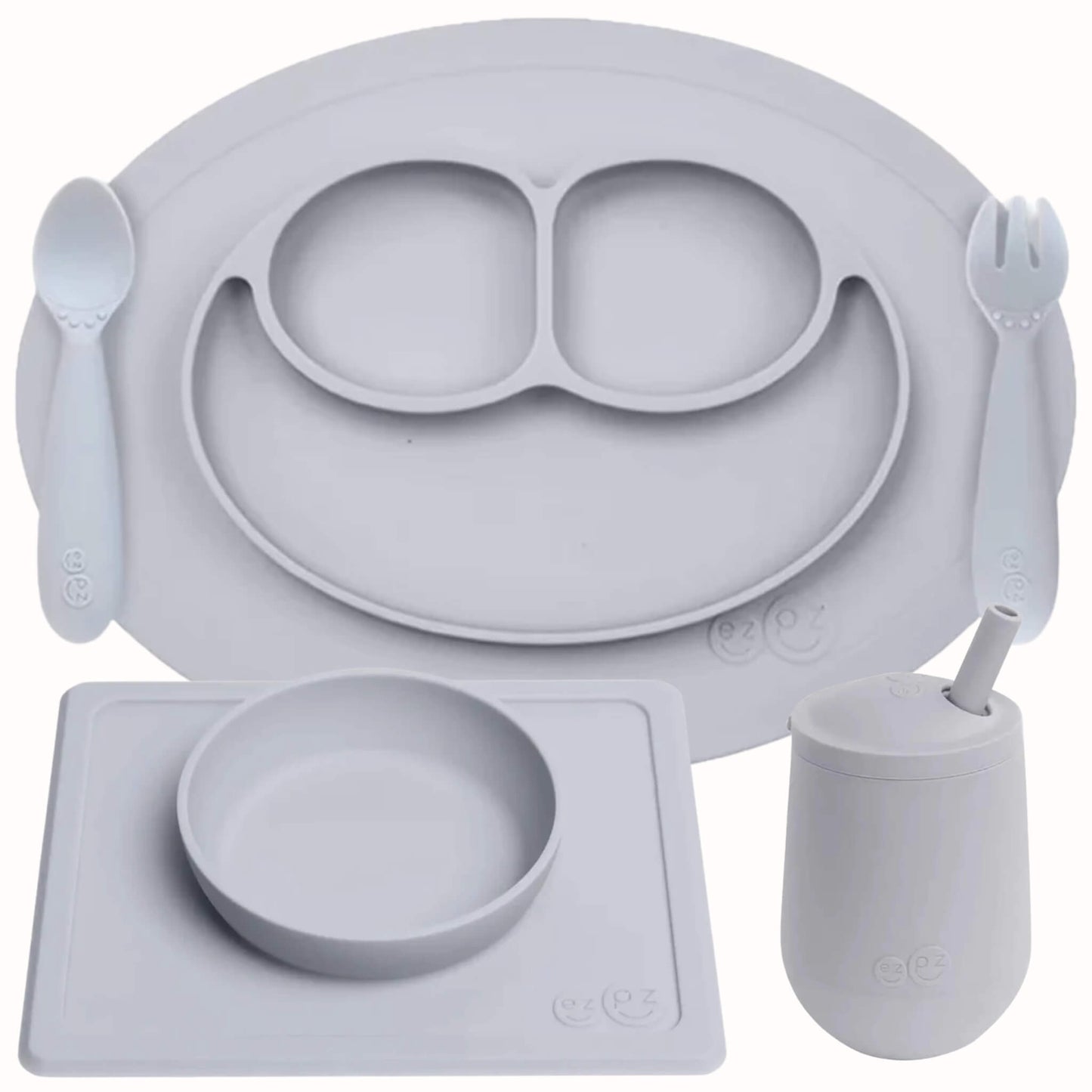 ezpz Self-Feeding Mealtime Bundle in pewter featuring a silicone mini mat with spoon and fork, suction bowl with placemat and mini cup with straw.