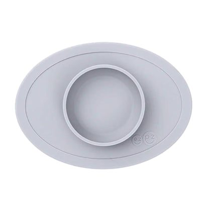 ezpz Tiny Bowl in pewter. An oval silicone placemat with a small round bowl built into the centre, designed for baby weaning and first foods.