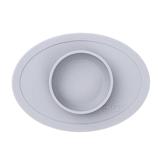 ezpz Tiny Bowl in pewter. An oval silicone placemat with a small round bowl built into the centre, designed for baby weaning and first foods.