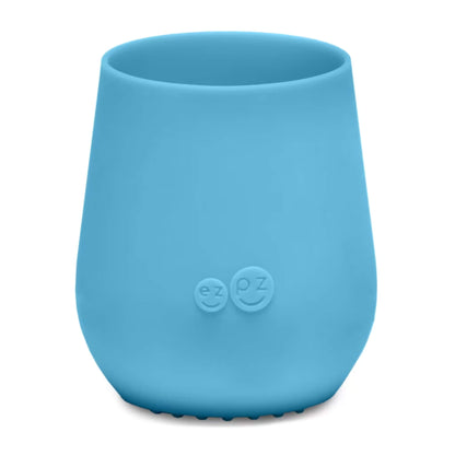 Ezpz Tiny Cup in blue, a small silicone training cup designed for babies and toddlers, shown empty against a plain background.