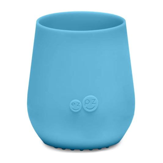 Ezpz Tiny Cup in blue, a small silicone training cup designed for babies and toddlers, shown empty against a plain background.
